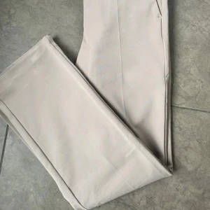 Beige kostymbyxor från Tiger of Sweden - OT Tiger of Sweden oanvända, alltså inget att anmärka på. Modell Noora 3 Strl 36, tts Mellanhög midja  Smal passform  Något bootcut  Hake och dragkedja  Öppna sidofickor  Stretch  45 polyester, 3 elastan och 52 eko bomull.