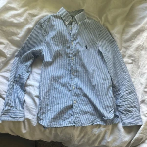 Blårandig skjorta från Polo Ralph Lauren - Säljer min brorsas blårandig skjorta från Polo Ralph Lauren. Skjortan är endast använd ett fåtal gånger. Skicket är mycket bra! Storlek 170. Storlek S