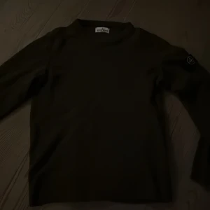Olivgrön långärmad tröja från Stone Island Junior - Säljer en olivgrön långärmad tröja från Stone Island Junior. Tröjan har klassisk rund hals och den ikoniska Stone Island-loggan på ärmen. Perfekt för dig som gillar stilrena och exklusiva plagg. Pris kan diskuteras!