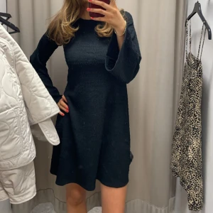 Svart klänning med utsvängda ärmar - Mysig svart stickad klänning med lång ärm och lätt utsvängd passform. Klänningen är lite öppen på ryggen! 💕