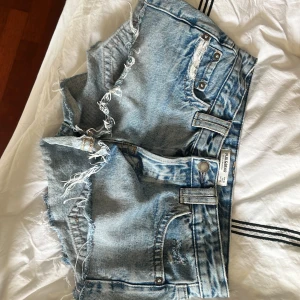 Ljusblå jeansshorts med fransar från Pull&Bear - Säljer dessa assnygga jeans shortsen som är lowwaisted.