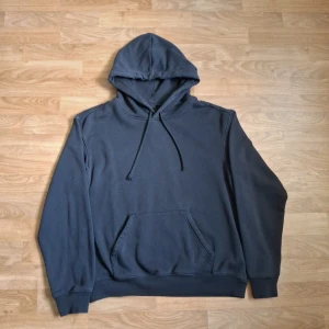 Svart hoodie från H&M - Säljer en svart hoodie från H&M i relaxed fit. Tröjan har huva med dragsko och en stor magficka framtill. Perfekt för dig som gillar en enkel och stilren look. Passar till det mesta och är riktigt skön att ha på sig.