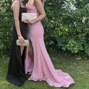 Rosa glittrig balklänning från Stacees - Säljer en fantastisk rosa långklänning från Stacees med glittriga paljetter, slits framtill och snörning i ryggen. Klänningen har smala axelband och figurnära passform, perfekt för bal eller fest. Materialet är syntet och klänningen har en elegant omlottkänsla. Den är från london!💗 endast använd en gång på min bal 