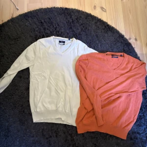 Två v-ringade tröjor från GANT - Säljer två stilrena v-ringade tröjor från GANT i premium bomull. En är Vit och den andra är orange. Båda har långa ärmar och ribbade muddar vid ärmslut och nederkant. Perfekta för lager-på-lager under hösten eller våren. Storlek M på båda 