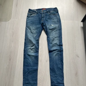 Blå jeans från Jack & Jones - Säljer ett par snygga blå jeans från Jack & Jones i modellen Glenn. De har en slim passform och klassisk femficksdesign. Perfekta för en avslappnad stil.