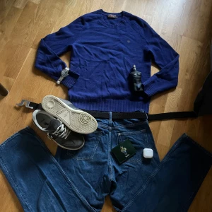 Blå loose fit jeans från H&M - Säljer ett par blå loose fit jeans från H&M med justerbar midja. Klassisk femficksmodell med raka, vida ben och knappgylf. Perfekta för en avslappnad och trendig look.