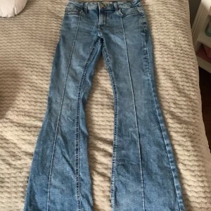 Blå bootcut jeans från Lindex - Säljer ett par klassiska blå bootcut jeans från Lindex med pressveck framtill och snygga bakfickor med lock. Jeansen har normal passform och gylf med knapp. Perfekta till din jeansgarderob!💗