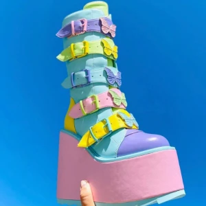 Y.R.U platåskor pastellfjärilar - Unika platåstövlar i pastellfärger med flera spännen och fjärilsdetaljer. Skorna har en hög platåsula i rosa och dragkedja bak. Säljer på grund av att min stil har ändrats och jag tycker det är synd att ett sånt fint par bara ska sitta på hyllan och damma 💕storlek 37 men jag som har storlek 38 ibland tycker dom är bekväma ändå 