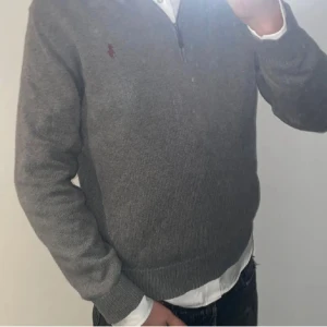 Ralph lauren tröja - Säljer en stilren grå tröja från Ralph Lauren med dragkedja vid halsen. Tröjan har långa ärmar och en liten broderad logotyp på bröstet. Perfekt för en avslappnad och snygg look. Storlek M