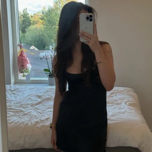Svart satin klänning från Zara - Säljer en svart satin klänning från Zara med smala axelband och lätt figurnära passform. Klänningen har en enkel och stilren design med mjukt, glansigt material och lätt utsvängd nederdel. Perfekt för dig som gillar minimalistisk stil.