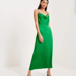 Grön långklänning med smala axelband - Säljer en snygg grön långklänning med smala axelband och lätt draperad urringning. Klänningen har en elegant och enkel siluett som ger en stilren look. Perfekt för balen!💕💕Helt oanvänd!!! Dragkedja i sidan. 