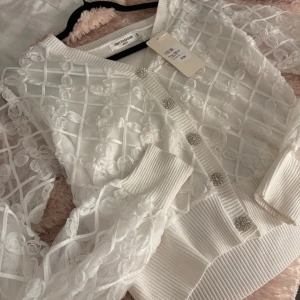 Vit oanvänd spets kofta från Ivy fashion  - Superfin vit kofta med transparent spets och blommönster. Koftan har långa ärmar, glittriga pärlknappar och ribbade muddar. Den är helt oanvänd och kvitto kan möjligtvis gå att hitta! Nypris 699kr. Storlek S/M men passar mig som har S. 