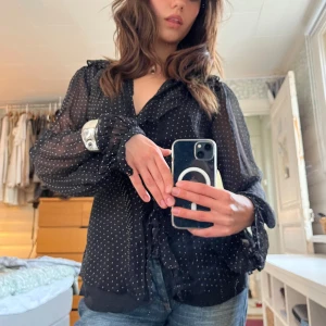 Prickig silkeblus  - Super söt prickig blus i 100% silke med utsvängda ärmar och rosettknytning i bak. Från Oasis i storlek M-XS (jag har storlek XS så blusen går att justera med banden). I mycket bra skick! 