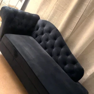 Mörkblå sammetssoffa - Elegant mörkblå soffa i sammet med knappar och en klassisk design. Perfekt för att ge vardagsrummet en lyxig känsla. Soffan har en mjuk och inbjudande yta med en stilren form.