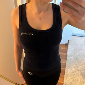 Svart ribbad topp från H&M Divided - Säljer en svart ribbad topp från H&M Divided.  Använd några gånger, vilket kan märkas på trycket men inget som annars är märkbart💕