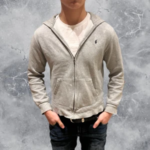 Ralph Lauren Full Zip Hoodie Grå - •Ralph Lauren Full-Zip Hoodie Grå. Skick: 8-9/10, Inga skador! Storlek: L ungdom 14/16 yrs = XS~, 155-165 cm. •Mått, axel-neråt: 54 cm, bredd: 44 cm. Modell: 173 cm, 63 kg. Sitter för litet på modellen! Authentic: ✅. Hör av dig vid frågor eller funderingar, mvh Hessler’s;)