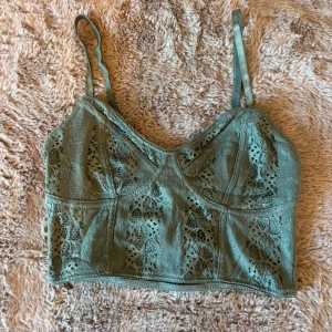 Grön spetslinne från Bik Bok - Säljer ett grönt spetslinne från Bik Bok i storlek XS. Perfekt för att lägga till en touch av elegans till din outfit.💚