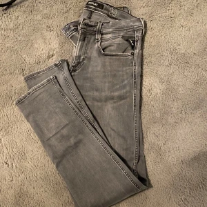 Grå jeans från Replay - Snygga grå jeans från Replay med en stilren design. De har en klassisk femficksmodell och en bekväm passform. Perfekta för en avslappnad stil. 