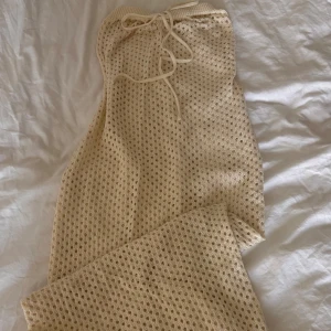 Strandklänning - En stickad lång beige strandklänning. Den har knytning uppe vid brösten och är genomskinlig. Aldrig använd 