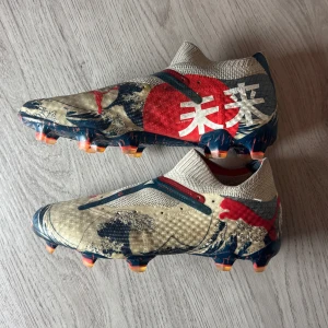 Puma Fotbollsskor - Säljer ett par Puma x Unisport Future 7 Ultimate "Great Wave" fotbollsskor i storlek 41. En limiterad utgåva som kombinerar Pumas toppmodell med en unik design inspirerad av den klassiska japanska vågen – framtagen i samarbete med Unisport.  ⚽ Detaljer: ✔ Modell: Future 7 Ultimate FG/AG ✔ Samarbete: Puma x Unisport ✔ Färg: Great Wave – blå/vit design ✔ Underlag: Fast Ground (FG) & Artificial Grass (AG) ✔ Passform: Formar sig efter foten ✔ Storlek: 41