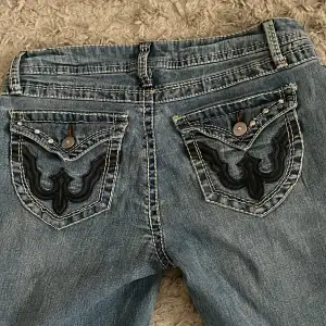 Säljer ett par lågmidjade blå jeans med snygga broderade detaljer på bakfickorna och diamantstenar både fram och bak. Köpta på A2 vintage men märket är Mudd💕 