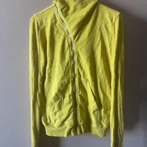 Rick Owens Yellow hoodie - Säljer en citrongul hoodie från DSquared2 med sned dragkedja och två fickor framtill. Jackan har långa ärmar och ribbade muddar. Perfekt för dig som vill sticka ut med en färgglad och unik look.