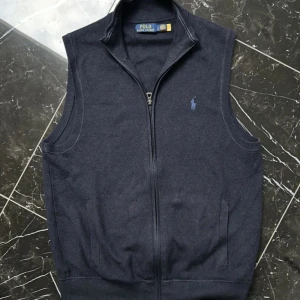 Ralph Lauren Väst - Hej, säljer denna stiliga mörblå väst från Ralph lauren. Har använt den i typ 1 år och den har liten skada på vänstra insidan då det är ett litet hål. Annars är den i bra skick, det är inga synliga skador dock. Priset kan diskuteras. 