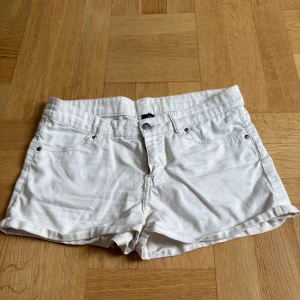Vita korta tjej shorts - Säljer ett par vita korta shorts med normal passform. De har klassisk design med fem fickor och knappgylf. Perfekta för varma sommardagar! Liten rosa fläck på baksidan se bild annars bra skick!