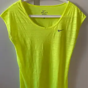 Träningstopp från Nike i neongul färg. Endast använd ett fåtal gånger. Storlek XS men upplevs som S. Lätt genomskinlig med tunt och luftigt material :)