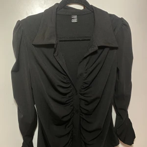 Svart tröja med knappar - Aldrig använd. Svart tröja med knappar och krage 