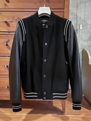 J.Lindeberg Varsity Jacket - Leeroy Wool Varsity Jacket  Varsityjacka / Bomberjacka i ull med armar i äkta läder. Hög kvalitet. Perfekt höstplagg! Knappt använd. Size S, aningen slim fit.  Bröstvidd: 49,5 cm Axelbredd: 43 cm Längd: 66 cm  DM vid frågor.