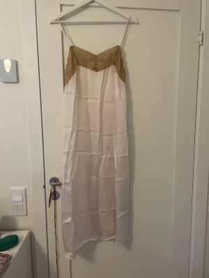 Rosa satinklänning med spets  - En ljus rosa (nästan cream) färgad klänning med brun spets och spagetti band. Den är helt oanvänd och från zara. Perfekt för en varm sommar dag 