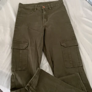 Gröna jeans i storlek 36 - Ett oanvänt plagg från H&M, köpt för 399kr. Militärgröna jeans med fickor, bakfickorna är äkta och fickorna på låren är också äkta fast det har knappar. Inte jätte stretchiga. Passar de som är runt 160-170cm lång