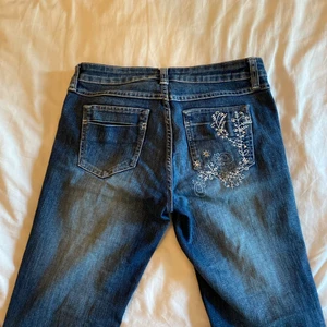 Skit snygga jeans med detaljer  - Ett par fett coola utsvängda jeans som jag köpte second hand. Jätte fina detaljer på fickorna och i perfekt skick. Fråga om du vill ha mer bilder!