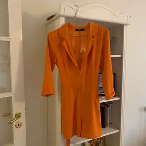 Orange playsuit från missguided, storlek 36. Djup urringning men snyggt med t.ex spets-bh under! Gjord i Polyester. Skärp som man kan ta av om man vill. Nyskick👍🏼