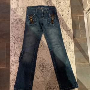 Säljer nu mina älskade jeans som jag älskade så när jag köpte dem. De är 2000-tals stil och de har många unika detaljer så som dess fickor med brun skin detalj! Low waist och utsvängda.🌟👖🪡 OBS kolla min bio innan köp!💥