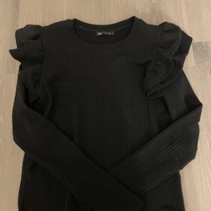 Svart volangtröja  - Svart tröja med volanger på axlarna från zara, storlek s säljer den för 70kr. Frakt ingår ej!