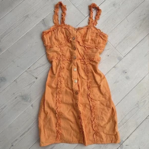 Orange sommarklänning - Säljer denna super vackra klänning från Urban Outfitters usa😍 älskar den, men den är tyvärr för liten och blev bara använd en gång:(. Den fina Färgen visas bäst på sista bilden 🍊 knapparna går att öppna/stänga 