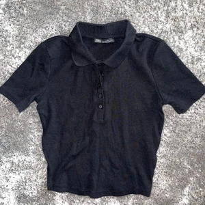 Svart T-shirt  - Användt denna T-shirt en gång men den är tyvärr inte min stil. Croppad thight med krage. Toppskick. Köparen står för frakten 