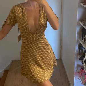 Prickig klänning i guldbrunt