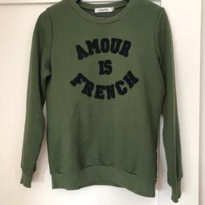 Mörkgrön collegetröja med amour is french - En superfin mörkgrön collegetröja från Jubylee med svart tryck där det står amour is french. Använd ett fåtal gånger och är i gott skick. 