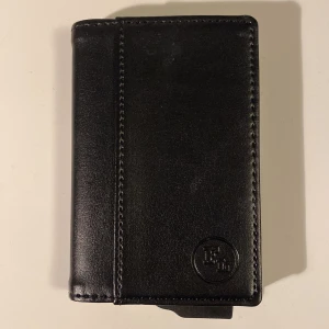 Plånbok - Plånbok/ korthållare  Svart Korthållare i metall med plats för ca 6 kort (beroende lite på hur tjocka kort) Helt oanvänd så den är i nyskick Nypris: 199 Frakt 30 kr 