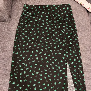 Lång svart/ grön blommig kjol  - Grön och svart blommig maxi kjol med slits i storlek M.