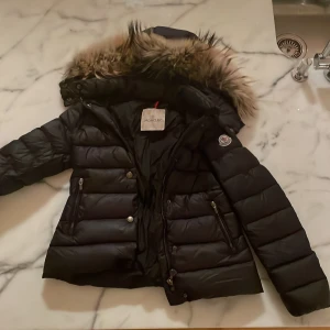 Moncler jacka - Jag säljer min jättefina jacka som jag använt sparsamt. Den är i mycket bra skick och är i barn storlek (10 år/xxs). Jackan är såklart äkta och ordinariepris ligger på 11 000kr. Jag säljer den för 2950kr. liten skada på armen,  kontakta för mer info ☺️