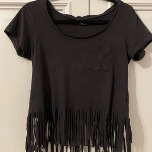 Svart T shirt med fransar - Svart t-shirt med fransar från Ginatricot. Mycket bra skick. Materialet liknar mocka. Något oversized. Inga slitningar eller defekter - ser ut som ny. 