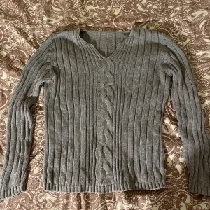 Grå stickad tröja - V-ringad grå stickad tröja med fina detaljer, lappen är borta men den är i storlek M