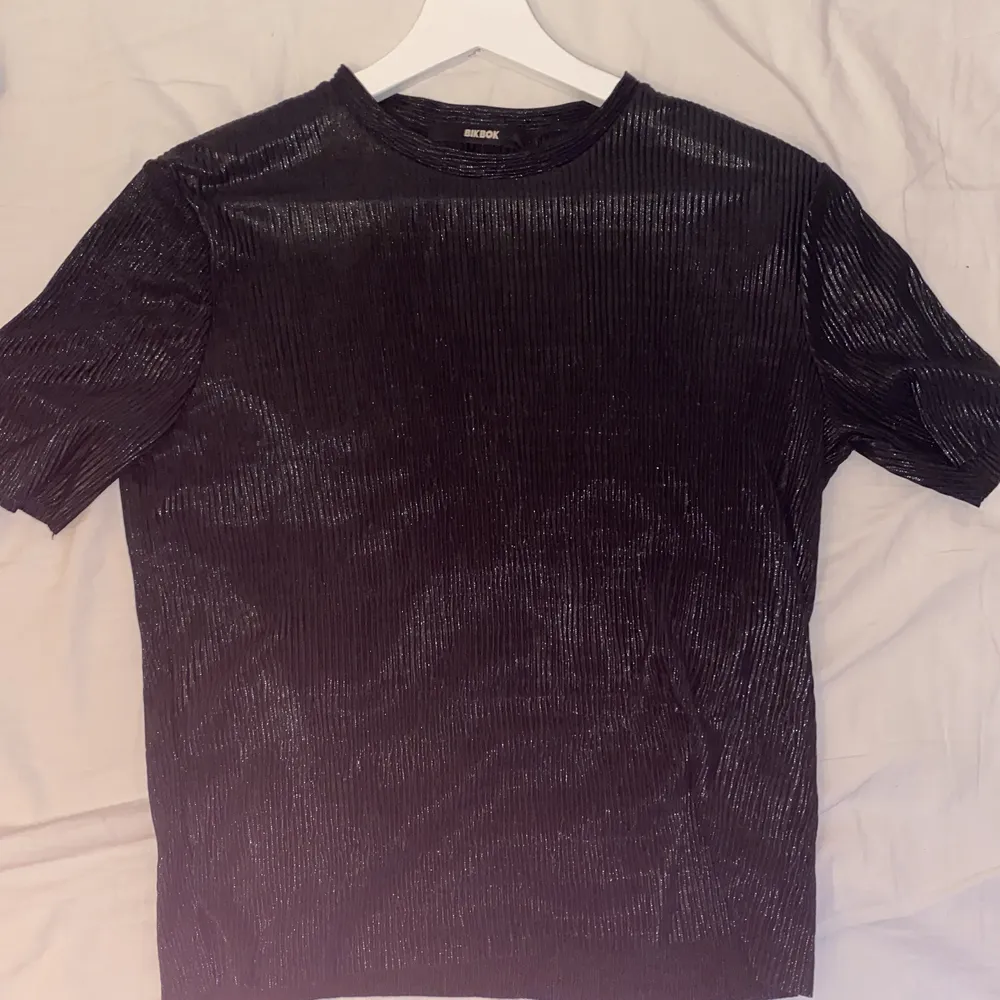 En svart skimrig tröja i ett skönt tunt material . T-shirts.