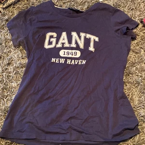 Gant marinblå T-shirt strl S - En fin Gant T-shirt med vitt tryck framtill. Knappt använd - trycket är inte slitet och det finns inga andra slitage / fläckar på den. Passar även XS-M. Nypris är 415 säljer för 250.