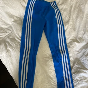 Adidasbyxor - Ett par kornblåa byxor/tights-liknande från Adidas. Knappt använda, stretchiga i storlek S/36. Har en dragkedja nertill så går att få till som en slits om man vill