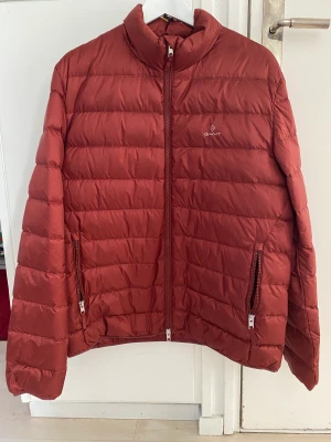 Gant lättvikt dunjacka - Säljer denna nya lättviktsdunjacka som min sambo fått i present och inte kunnat lämna tillbaka. Roströd i färgen. Nypris 2500kr. 